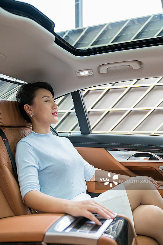 年轻女子坐在汽车后座休息图片素材