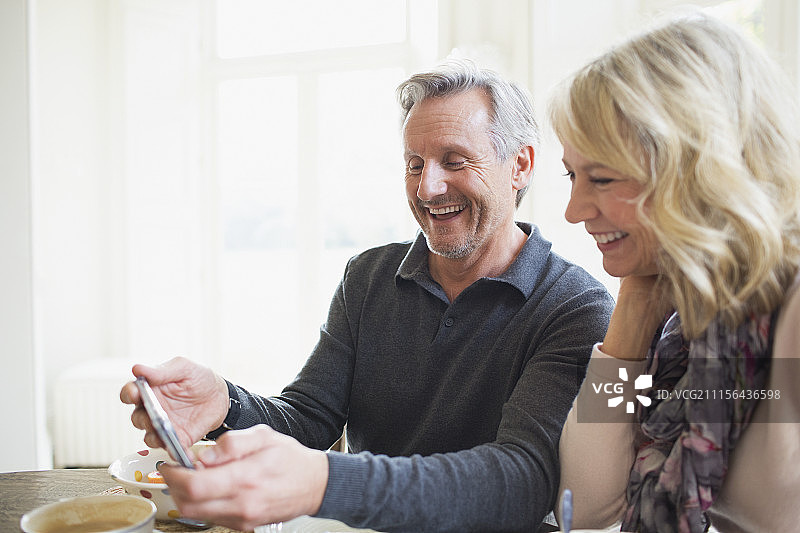 微笑的中年夫妇使用智能手机图片素材