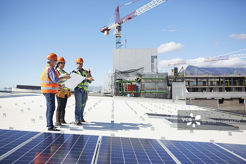 工程师在阳光明媚的发电厂查看太阳能电池板蓝图图片素材