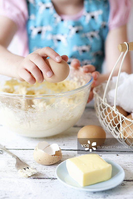 儿童将鸡蛋打入搅拌碗中图片素材