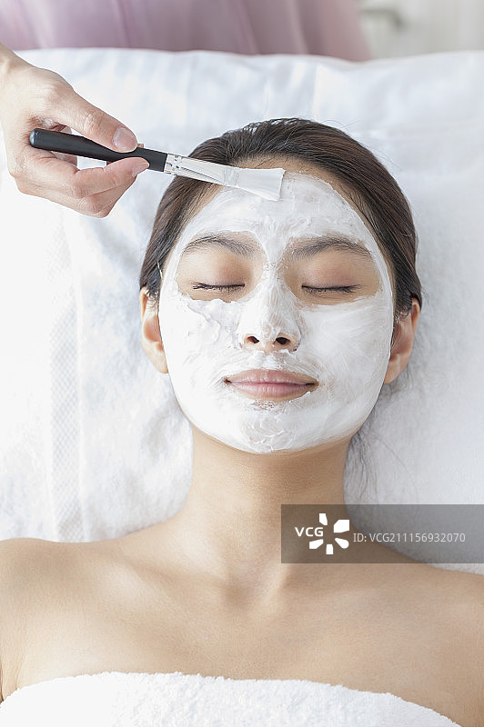美容师在帮年轻女人敷泥状面膜图片素材
