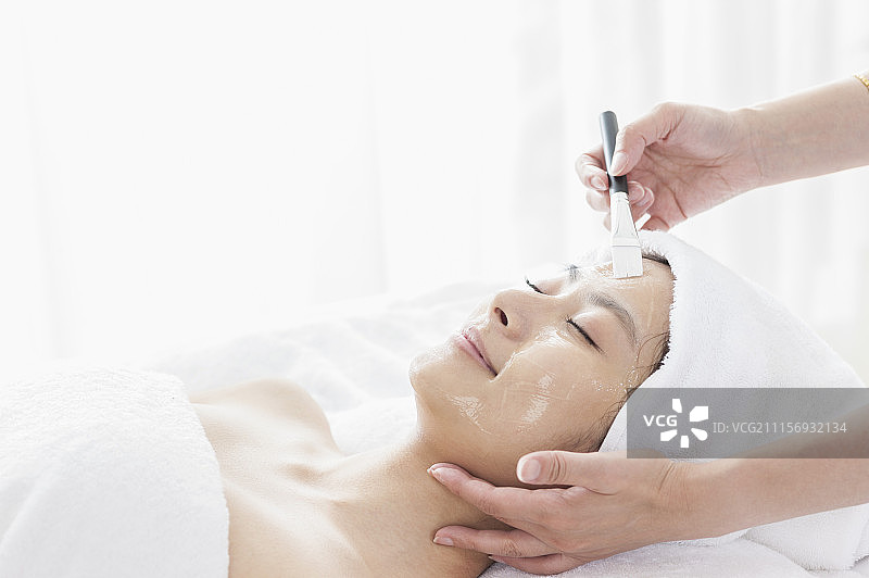 美容师在帮年轻女人敷泥状面膜图片素材