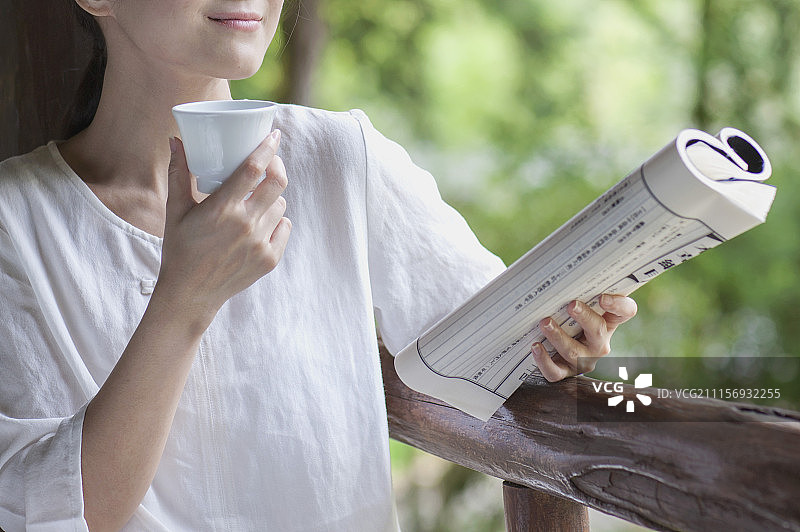 年轻女人拿着古书边喝茶图片素材