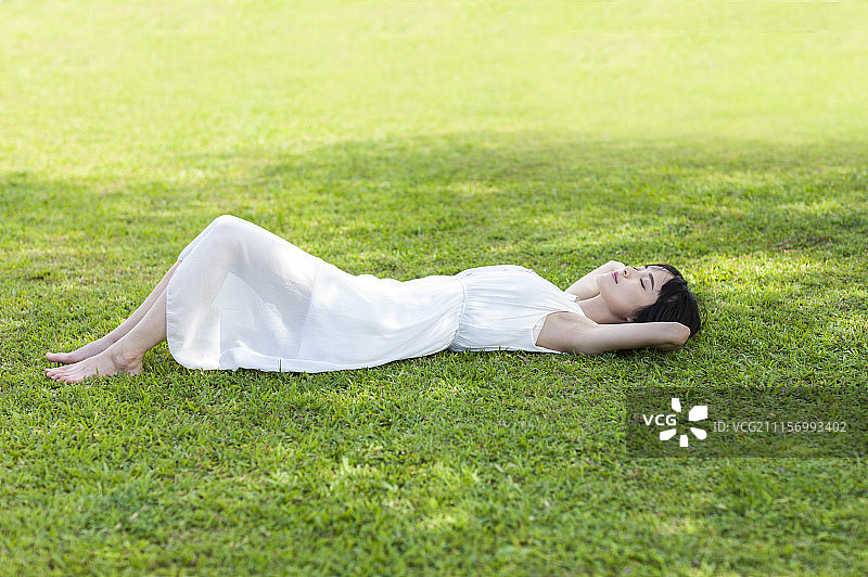 年轻女人躺在草地上睡觉图片素材