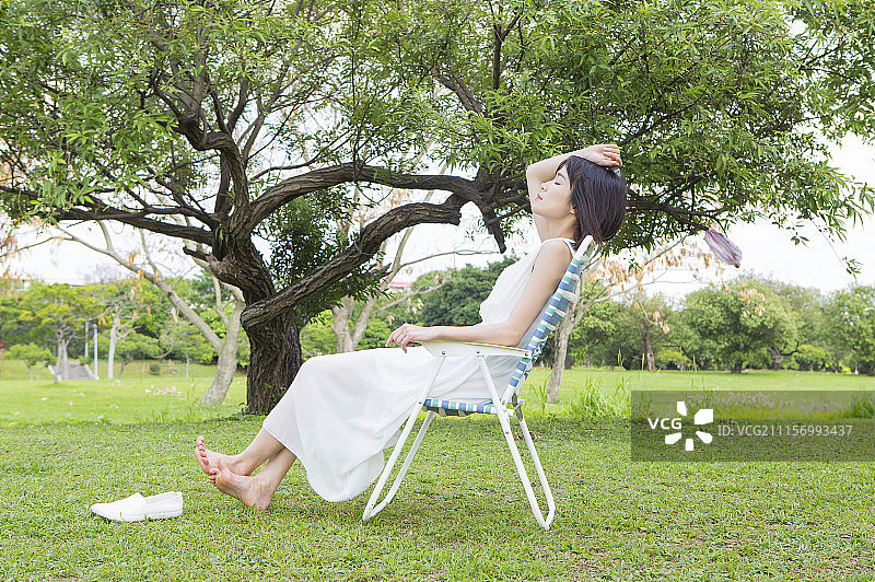 年轻女人坐在躺椅上做日光浴图片素材