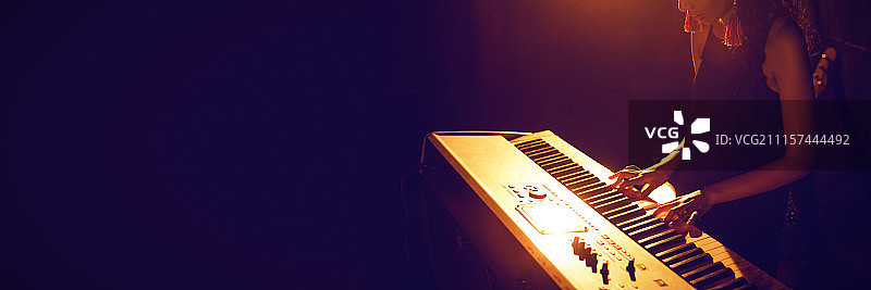 在灯光照射的俱乐部里弹钢琴键盘的女音乐家图片素材