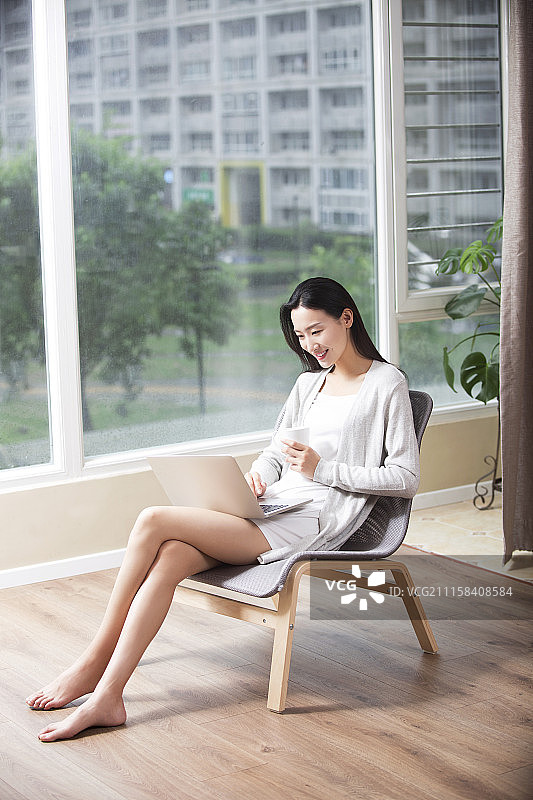年轻女子在家使用笔记本电脑图片素材