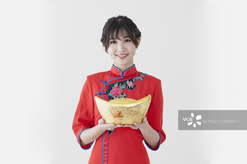 年轻女人穿旗袍拿着金元宝图片素材