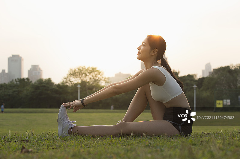 年轻女人坐在草地上拉筋图片素材
