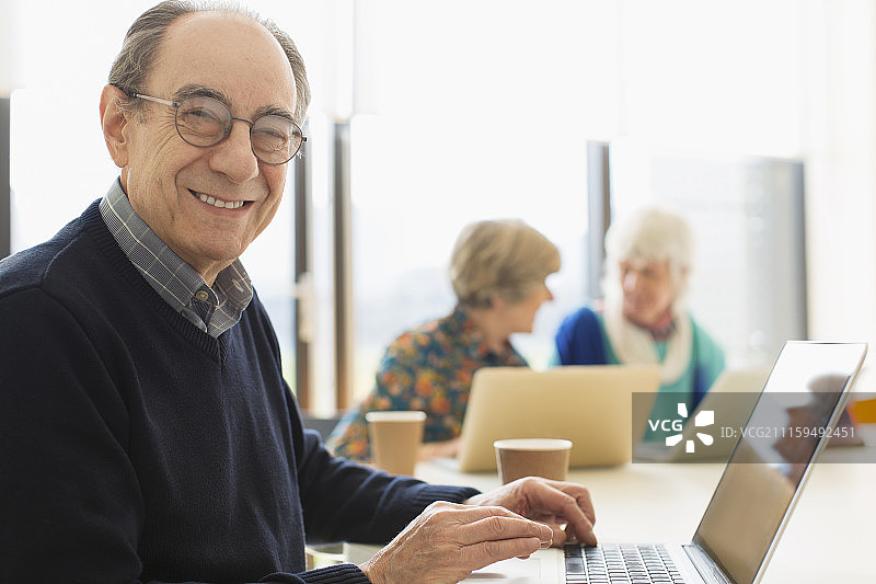 会议室里笑容满面、自信的年长商人使用笔记本电脑肖像图片素材
