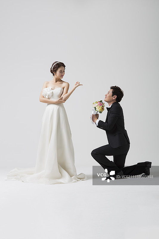 婚礼情侣，男子向女子求婚，手捧花束的摄影图片素材