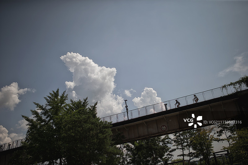 情侣戴着头盔骑自行车经过桥的摄影照片图片素材