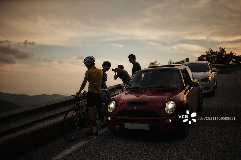 日落时分山路上的汽车与行人摄影图片素材