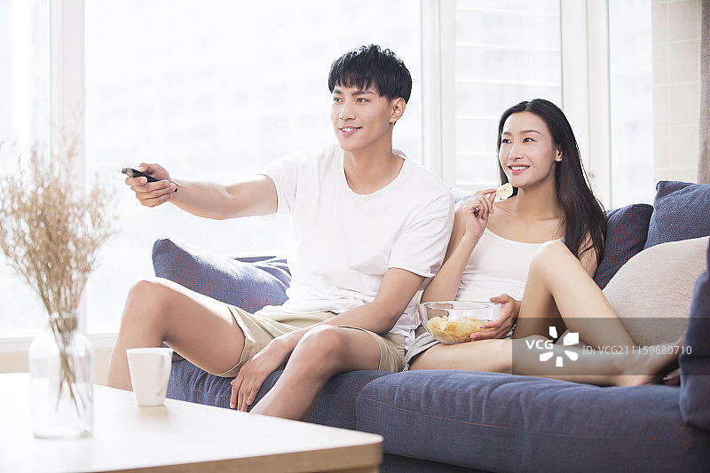 快乐的年轻情侣在家看电视图片素材