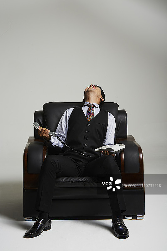 男子穿西装坐在沙发上生气地打电话的摄影作品图片素材