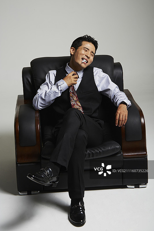 坐在沙发上，感到窒息的西装男人摄影图片素材