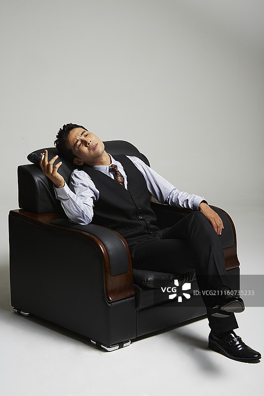 男人穿西装坐在沙发上吸烟的照片图片素材