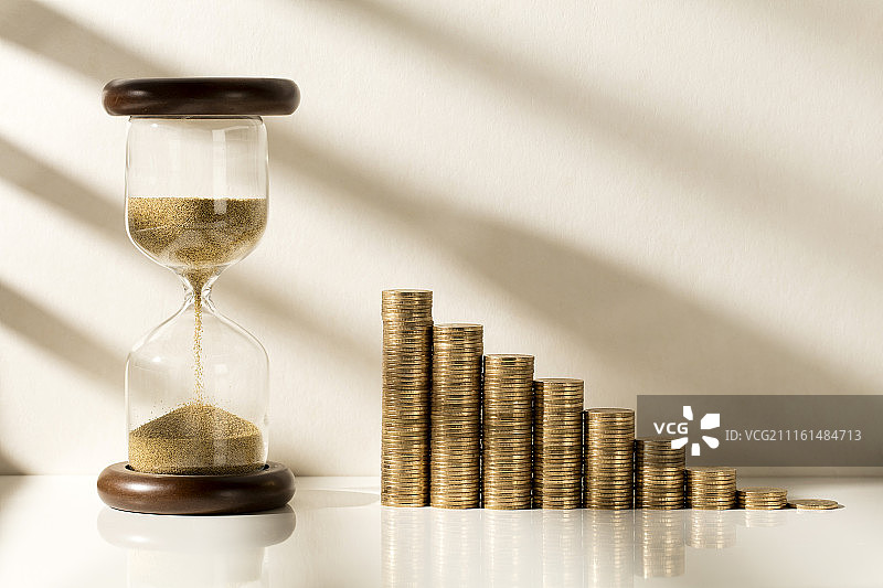 阳光照射的沙漏和硬币阶梯图片素材