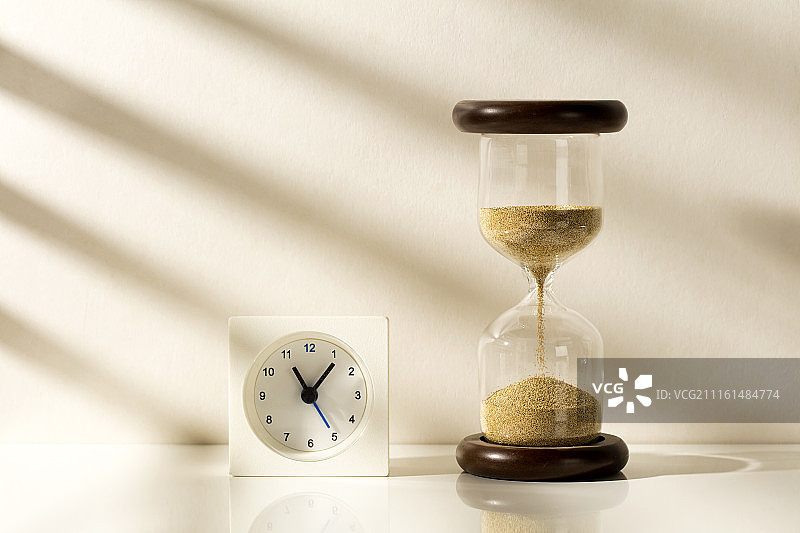 阳光照射的钟表与沙漏图片素材