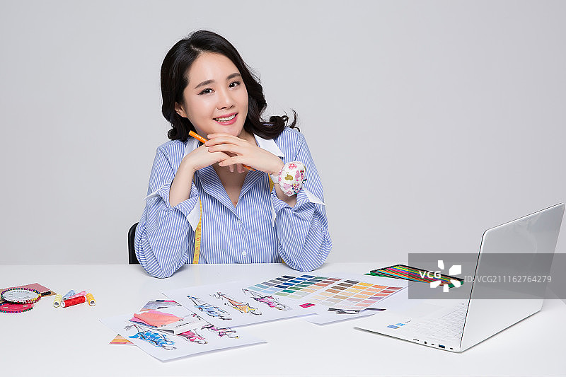 年轻女时装设计师在白色背景上使用平板电脑工作图片素材