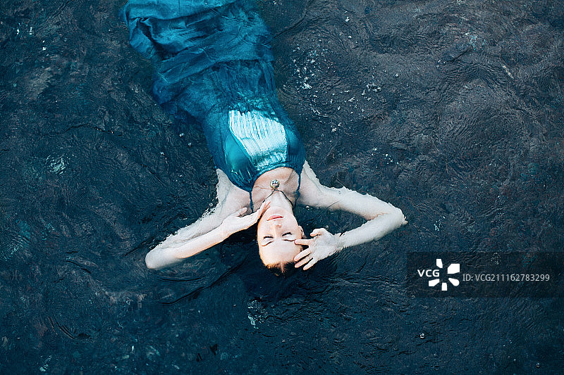 穿着连衣裙躺在水里的女人图片素材