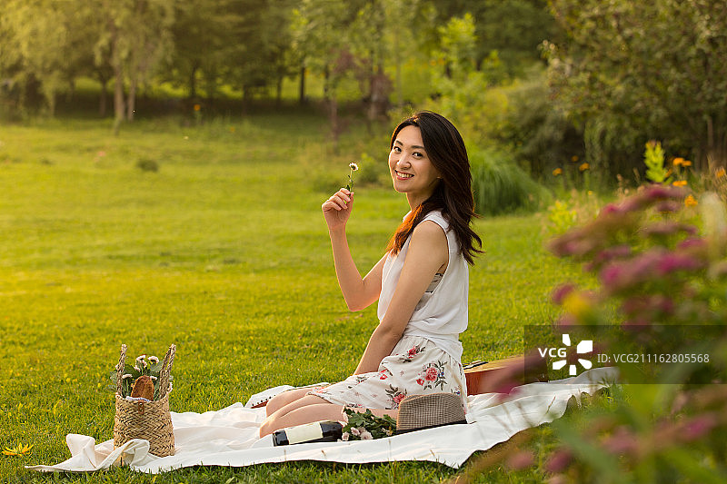 年轻女子坐在草地上野餐图片素材