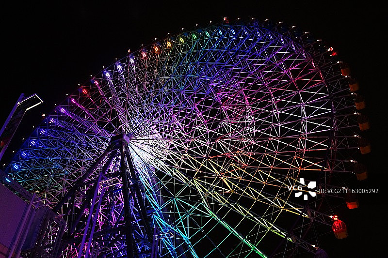 夜间带有彩虹灯的摩天轮的低角度视图图片素材