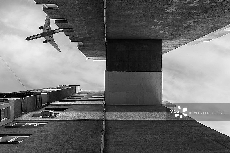 仰视视角：飞机飞过城市上空图片素材