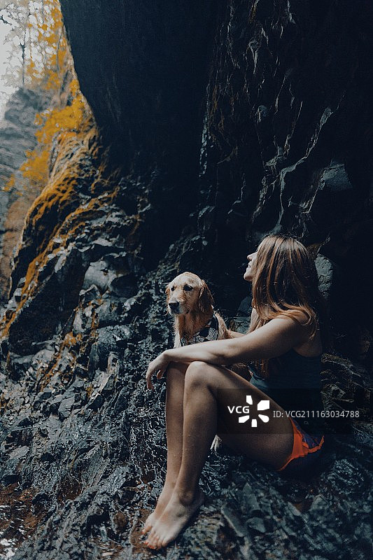 女子与金毛犬坐在俄勒冈州洞穴中，美国图片素材