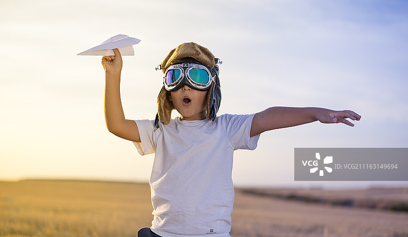 戴飞行员帽，拿着纸飞机的男孩肖像图片素材