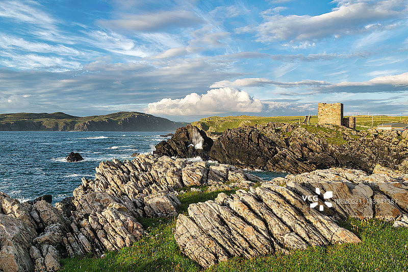 多云天气中多岩石海岸上的古老废墟图片素材