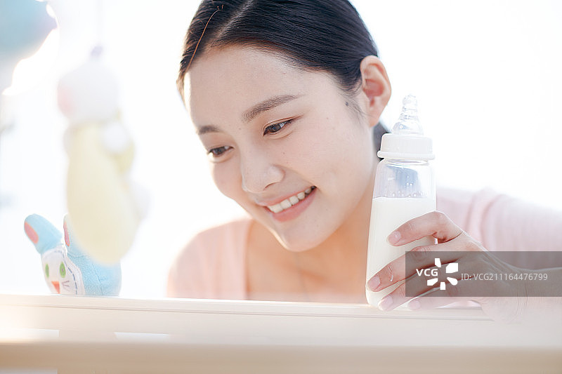 年轻妈妈拿着奶瓶图片素材