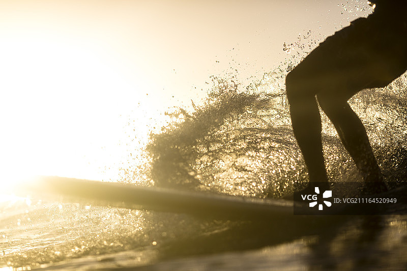 日落时分男子玩长板冲浪的下半身剪影图片素材