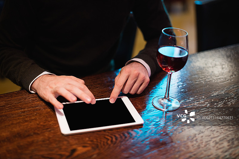 在柜台上用平板电脑和酒杯的商人图片素材