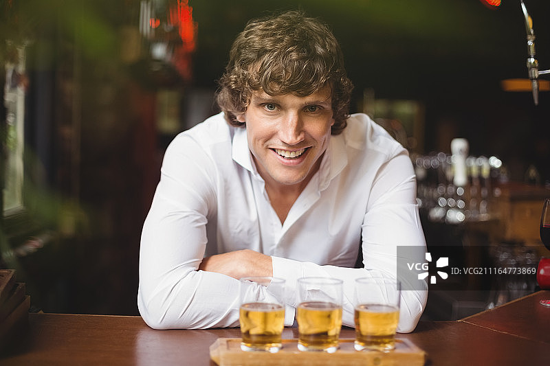 在吧台拿着一盘威士忌酒杯的酒保肖像图片素材