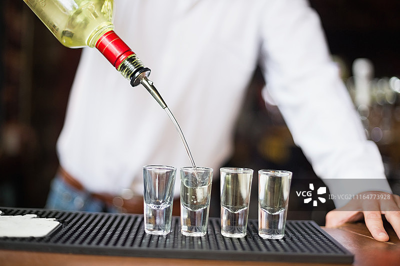 调酒师将龙舌兰倒入小玻璃杯特写图片素材