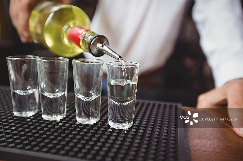 调酒师将龙舌兰倒入小玻璃杯特写图片素材