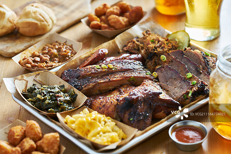 德克萨斯风味烧烤拼盘，含熏牛胸肉、圣路易斯排骨、手撕猪肉、鸡肉、香肠和配菜图片素材