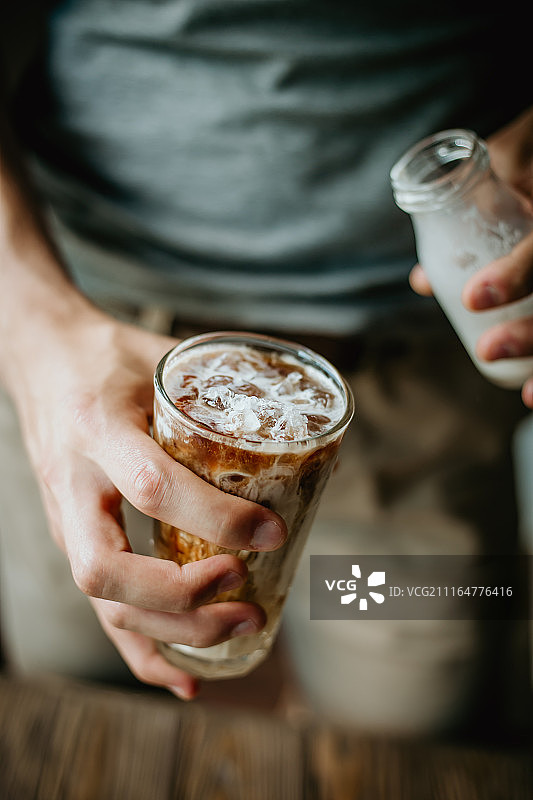 男人在冰咖啡里倒牛奶图片素材