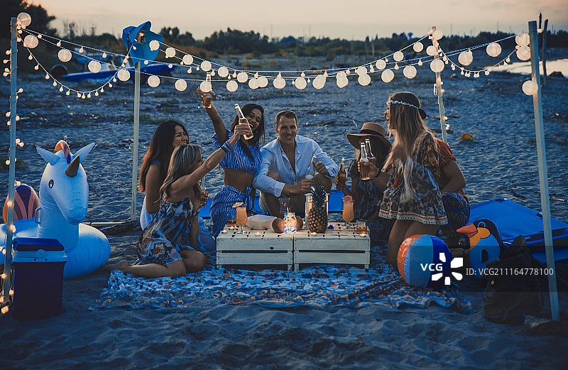 朋友们在日落时分的沙滩上聚会图片素材