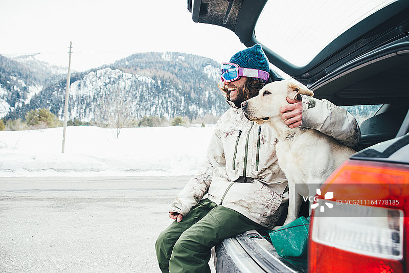 朋友们在雪山上和狗玩耍图片素材