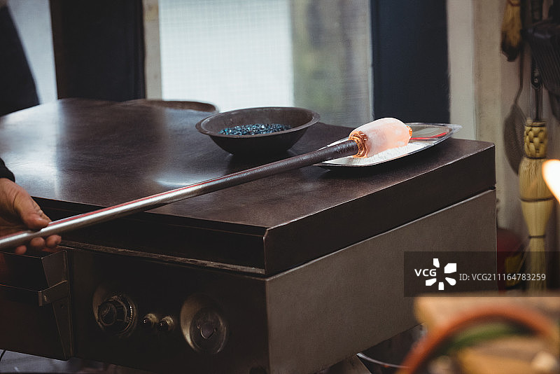 吹玻璃工人于制模台滚动熔融玻璃图片素材