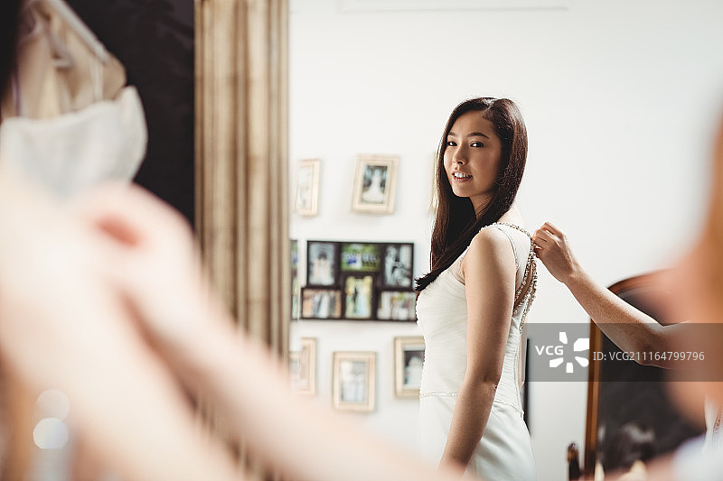 女人在创意设计师的帮助下试穿婚纱图片素材