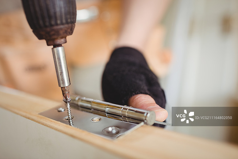 木匠拧紧木门铰链上的螺丝图片素材