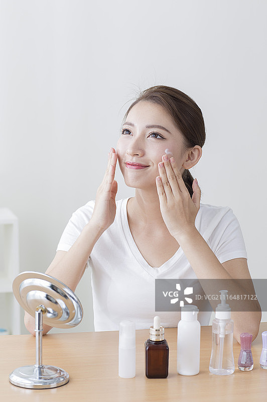 年轻女人在脸上涂抹保养品图片素材