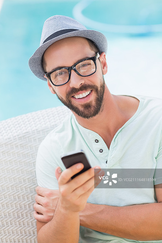 快乐的英俊男子看着镜头并拿着智能手机图片素材