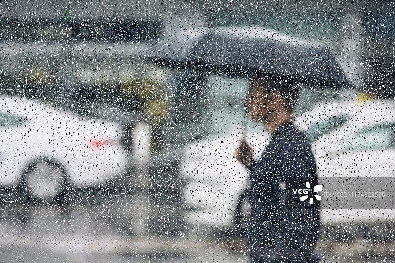在玻璃后面拿着雨伞的男人图片素材