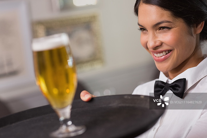 漂亮的女服务员端着一杯啤酒图片素材