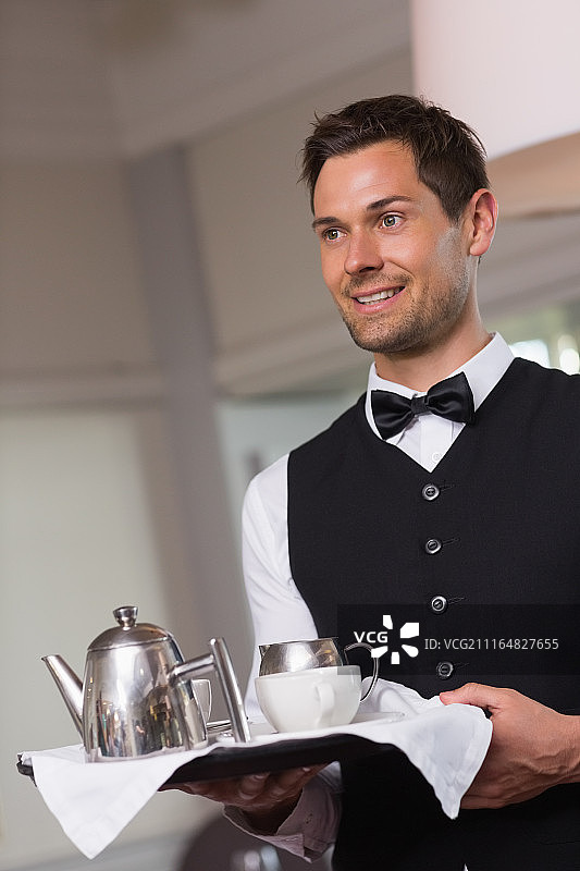 英俊的服务员托着托盘，里面放着下午茶图片素材