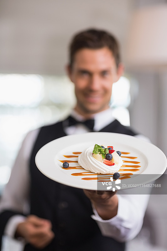 英俊的男服务员展示甜点盘图片素材